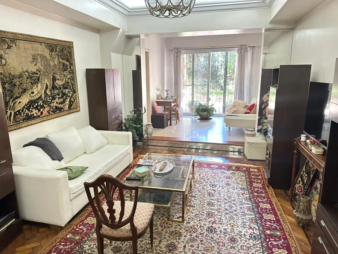 El living del departamento de Agüero al 1700: parquet en espiga, la alfombra bordó y el patio al fondo